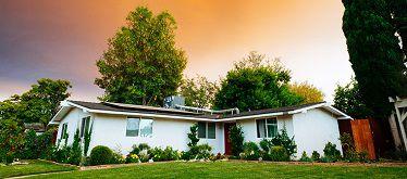 House with front lawn and surrounding trees.